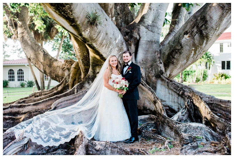 Bride and groom pose for formal photos in front of banyan tree in Estero, Florida.