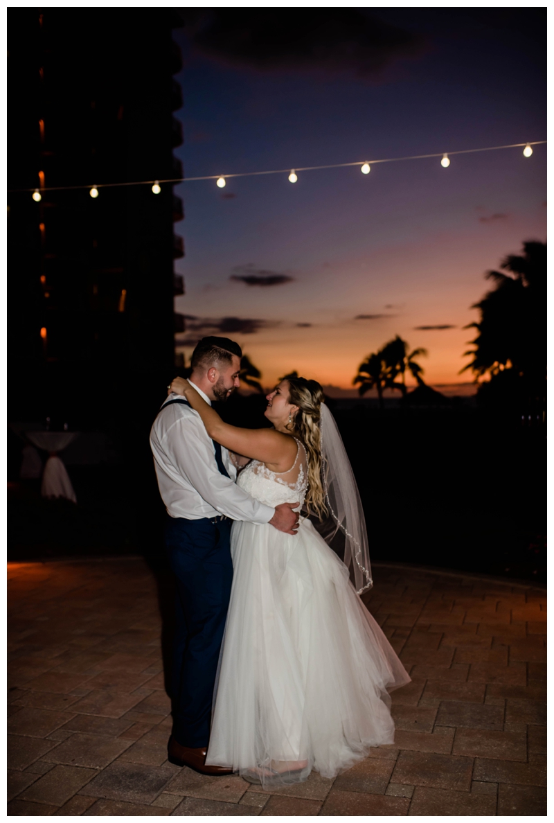 Bride and groom dance under string lights as the beach sun sets in Marco Island, Florida.