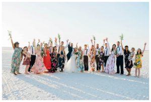 Large group of bride, bridesmaids and bridal party celebrate excitedly on Marco Island Beach.