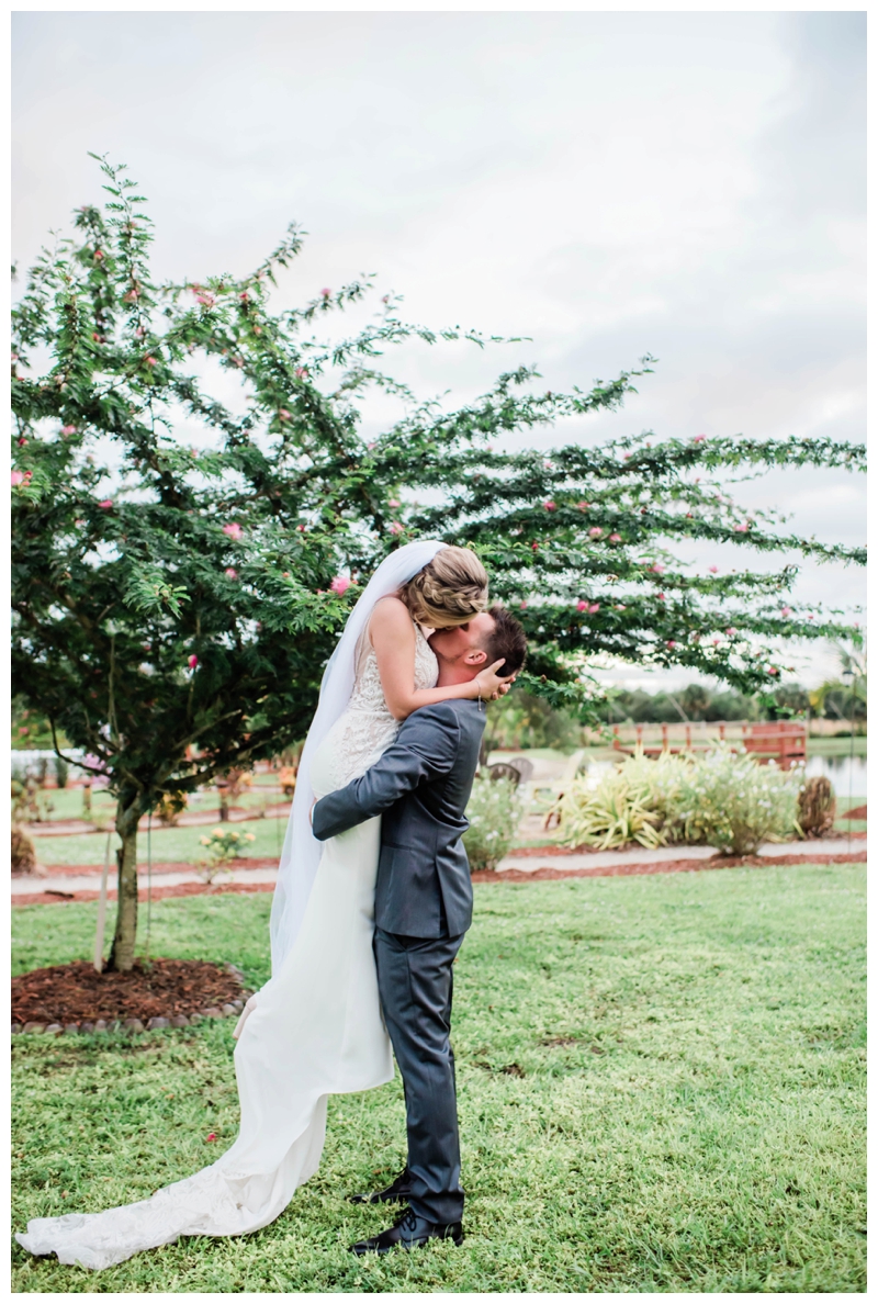 Groom lifts bride in loving kiss on wedding day in Bonita Springs, Florida.