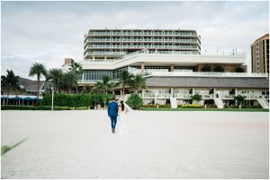 Bride and groom walk hand in hand down the beach at JW Marriott Marco Island in Florida.