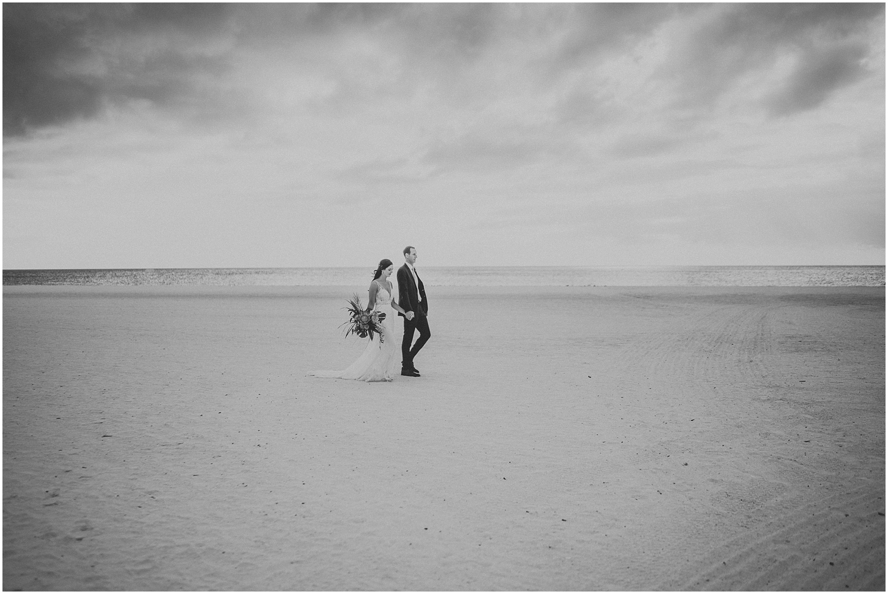 Bride and groom walk down the beach on wedding day at JW Marriott Marco Island in Florida