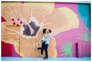 Engaged couple laughs in front of floral graffiti wall in Downtown Fort Myers.