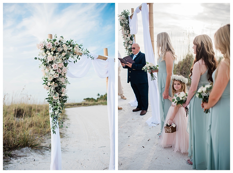 Arbor with draped white fabric and pink, ivory and green florals stands in the sand for Florida beach wedding ceremony