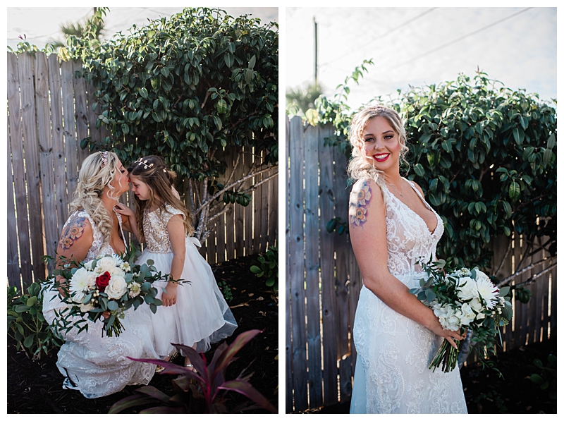 Bride kisses flower girl on forehead in garden wedding setting.