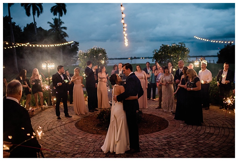 Bride and groom stand among all wedding guests under twinkle lights and Florida skies