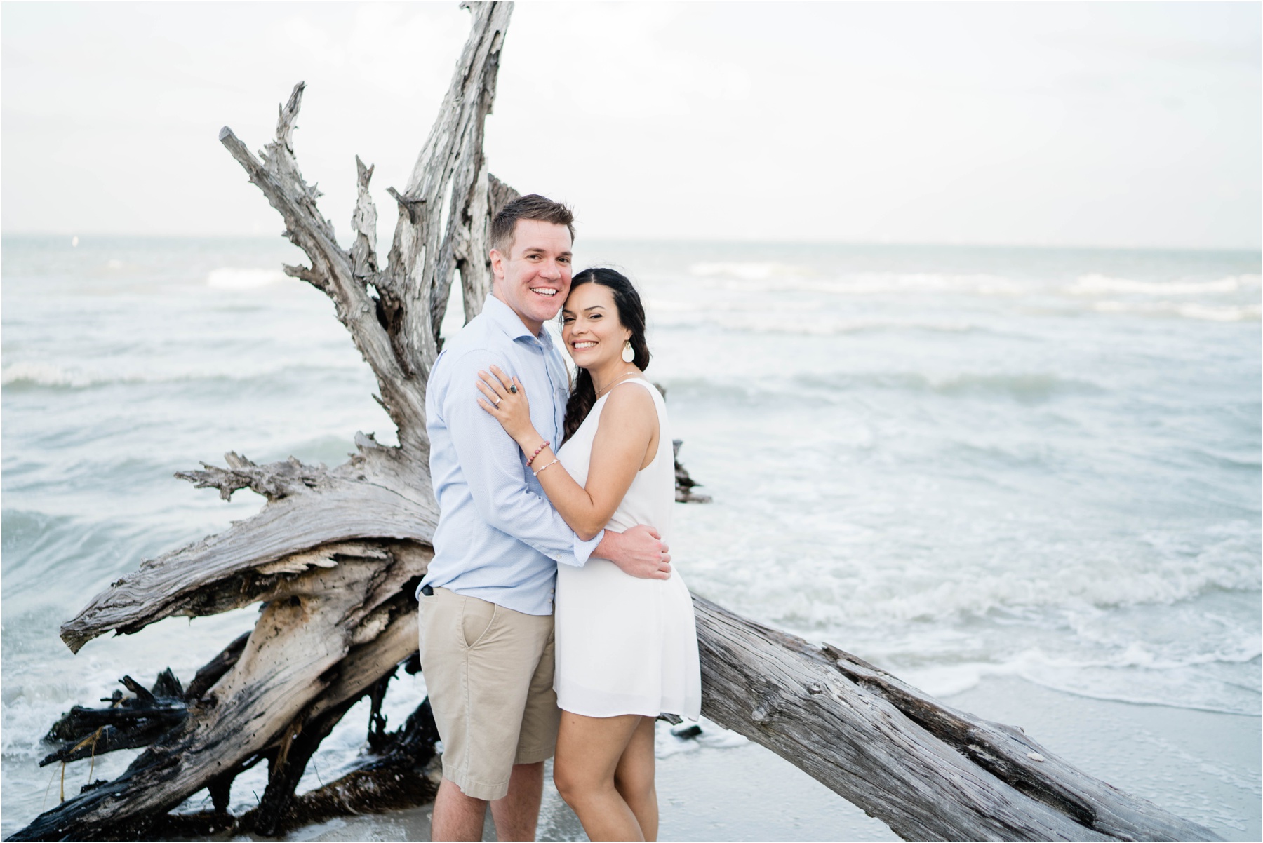 Couple embraces in front of driftwood during Sanibel Island engagement session