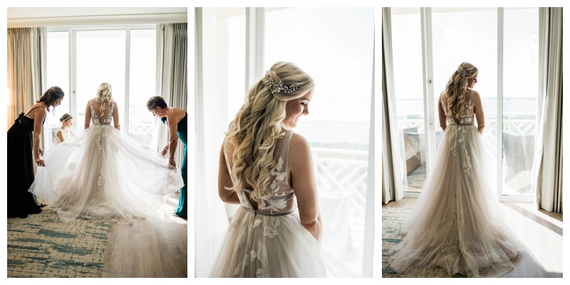 Florida bride stands in bridal suite as mother and friends fluff her gown
