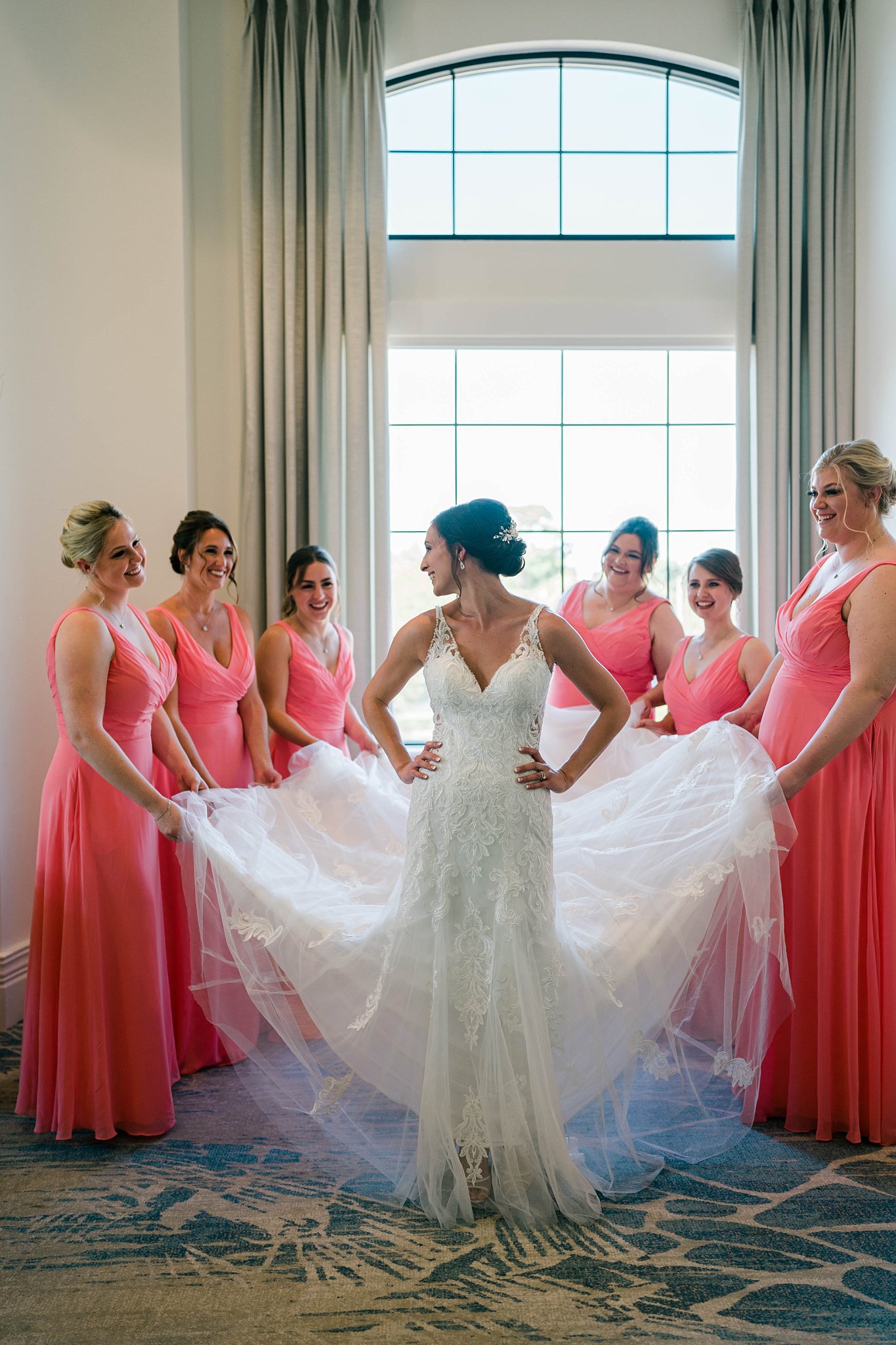 Bride stands with bridesmaids in coral bridesmaids gowns during South Florida wedding