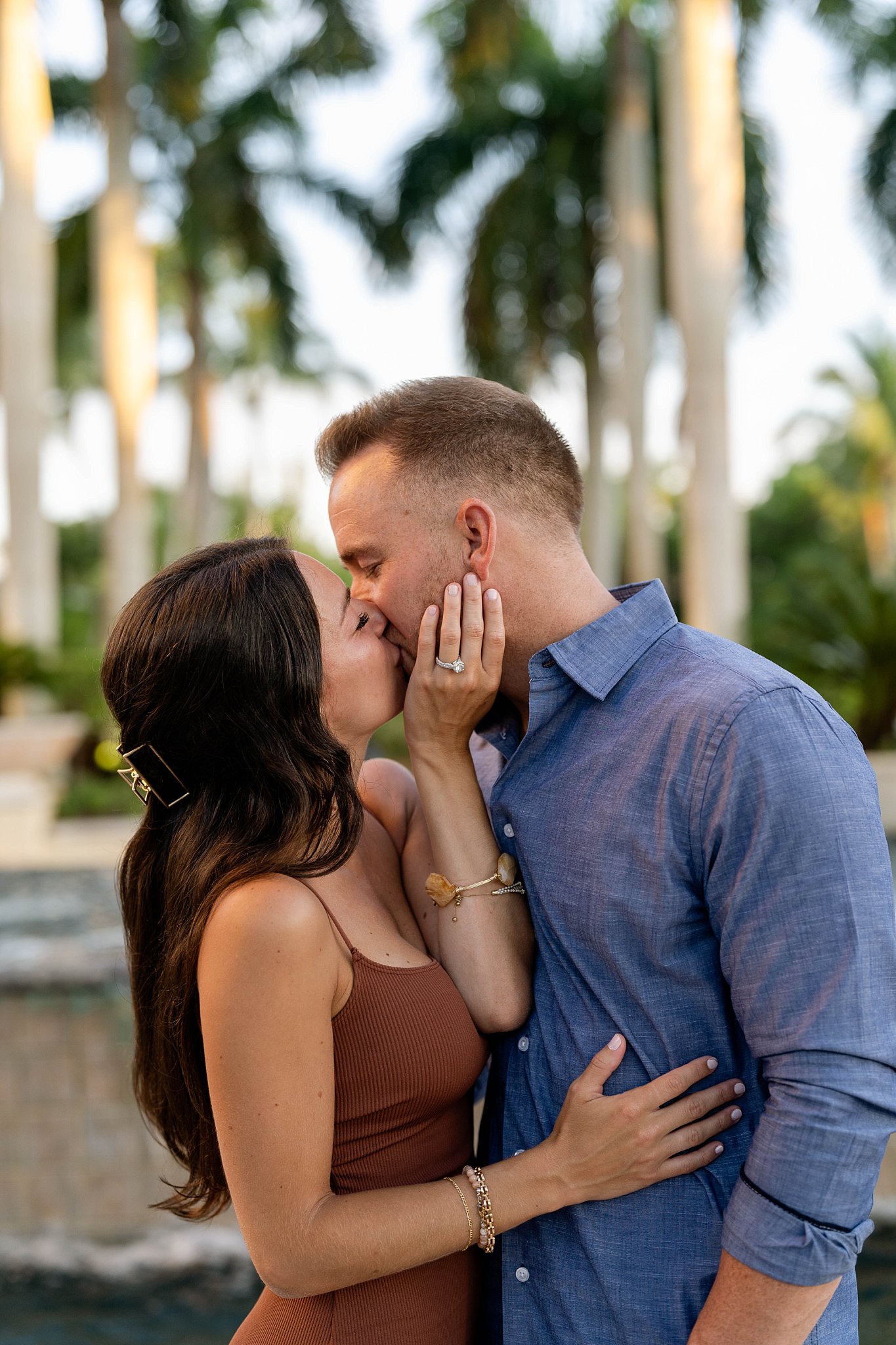 Bonita Springs Florida engagement portrait couple embraces and kisses while bride shows off engagement ring