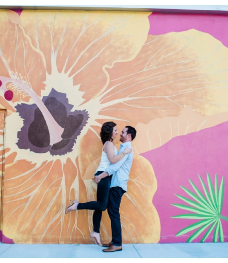 Engaged couple laughs in front of floral graffiti wall in Downtown Fort Myers.