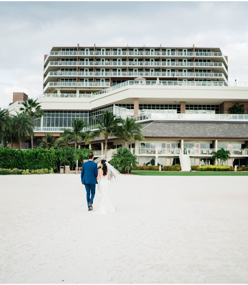 Bride and groom walk hand in hand down the beach at JW Marriott Marco Island in Florida.